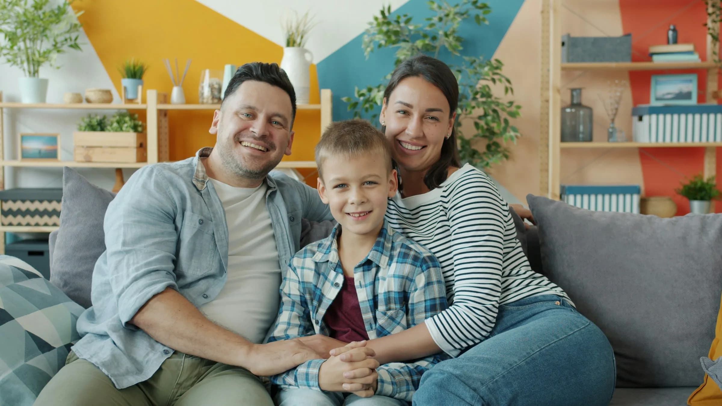 Father, mother and son smiling on their living room sofa