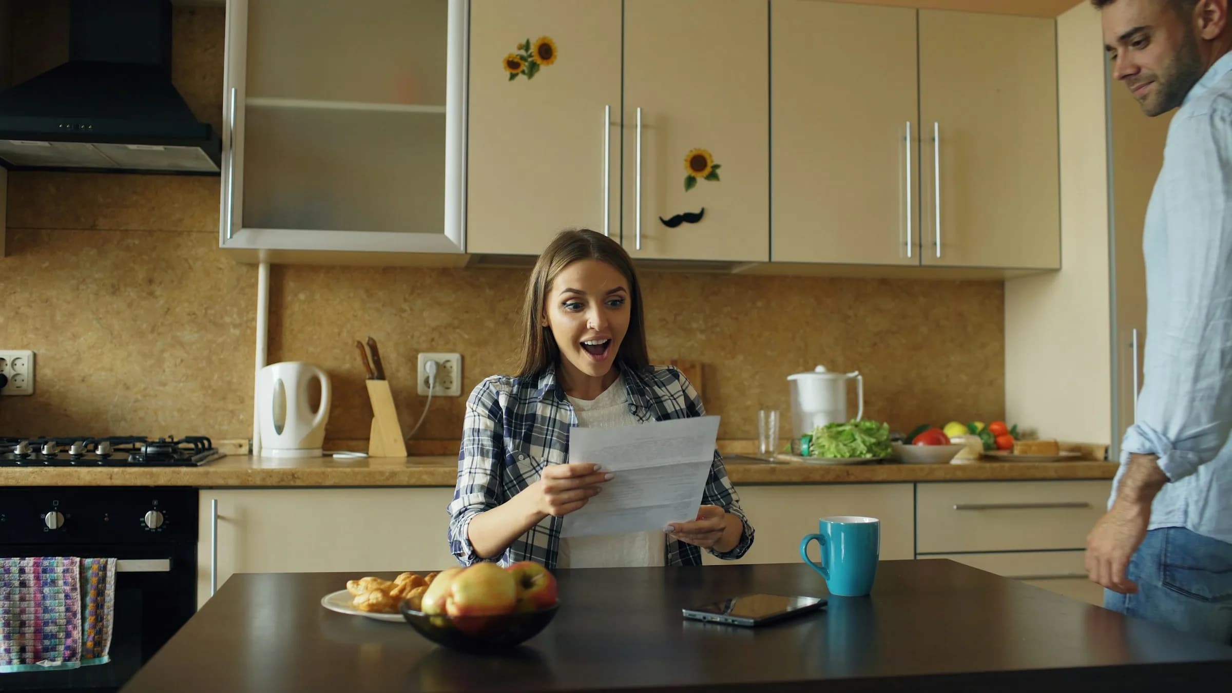 Couple reading a letter with good news in their kitchen at home