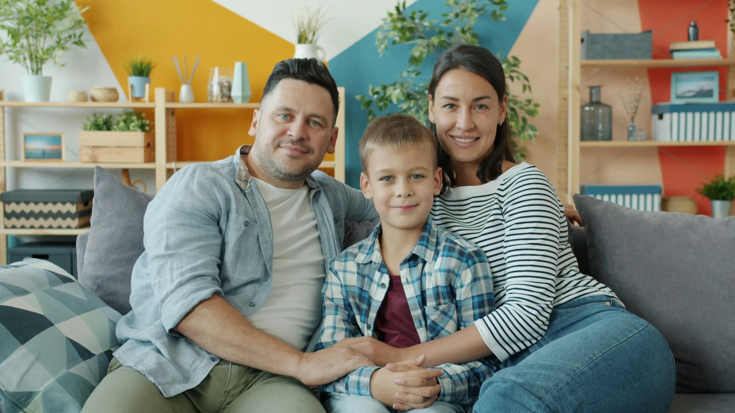Madre, padre e hijo sentados en el sofá de su sala, sonriendo relajados